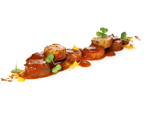 Wegańska kiełbasa curry Wegański zamiennik kiełbasy na bazie białka grochu, w owocowym, pikantnym sosie curry o smaku mango.