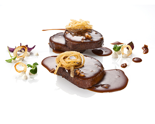 Geschmorter Zwiebelrostbraten Rinderbraten in herzhafter Rotwein-Zwiebel-Jus, in Scheiben geschnitten.