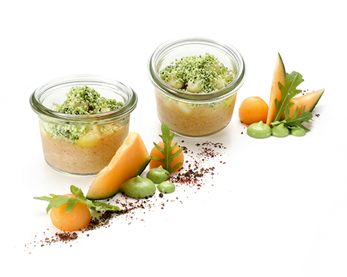 Melonen-Vanille-Gazpacho geliert, garniert mit Mozzarella und Zitronen-Kräuter-Crumble, im kleinen Glas.