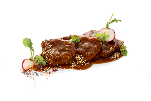 Vegan seitan roast in a wheat protein-based beer sauce, refined with grainy mustard, rosemary and thyme, sliced.