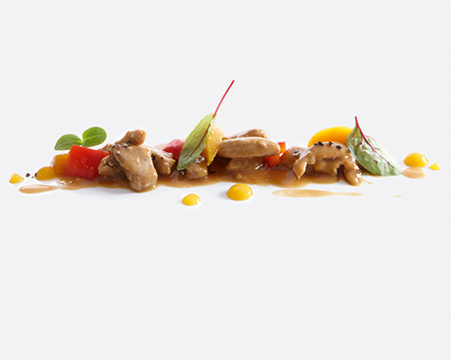 Sliced pork in a peach and pepper sauce with peach slices and pieces of sweet pepper.