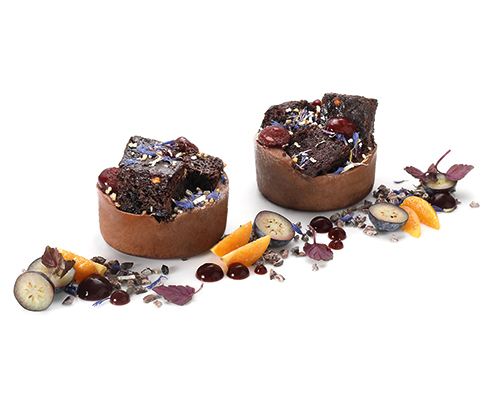 Vegan Dark Chocolate saftig gebackener Brownie auf veganer Zartbitterschokoladencreme, verfeinert mit fruchtigem Beeren- Gel und Kornblumenblüten, ø 5 cm.