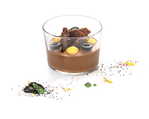Crispy Chocolate dark chocolate mousse, with crispy base pieces, black candied olives and orange sauce, in a Bodega glass.