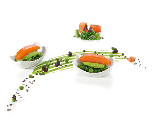Smoked salmon loin on pea wasabi with seaweed salad, in a rectangular dish.