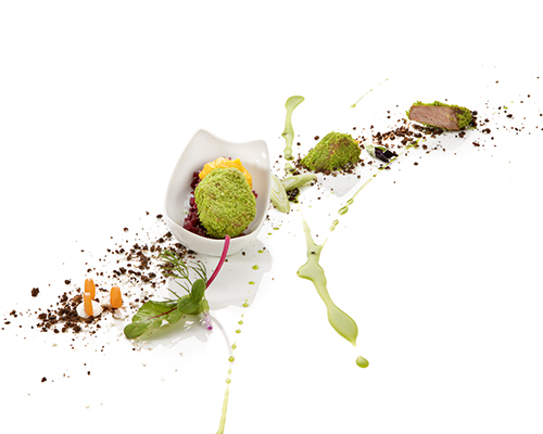 Policzki wieprzowe na czerwonej kapuście i musie z marchwi i tymianku w panierce z orzechów laskowych i ziół, w prostokątnym naczyniu.