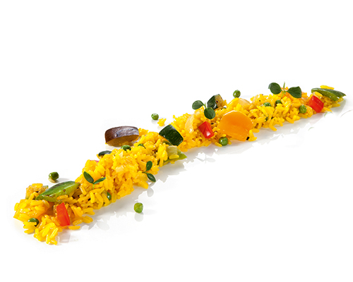 Wegańska paella z ryżu długoziarnistego z papryką, cukinią, bakłażanem i cebulą, doprawiona kurkumą.