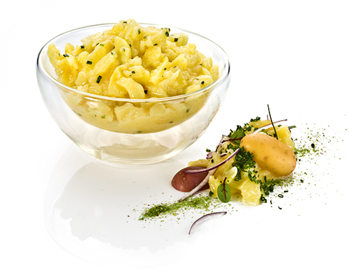 Grasbrunner Kartoffelsalat würzig, säuerlich, mit Weinessig und Schnittlauch, in Essig-Öl-Dressing.