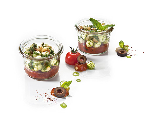 Tomato compote and mozzarella with green pesto and pine nuts, negative for preserving jar.